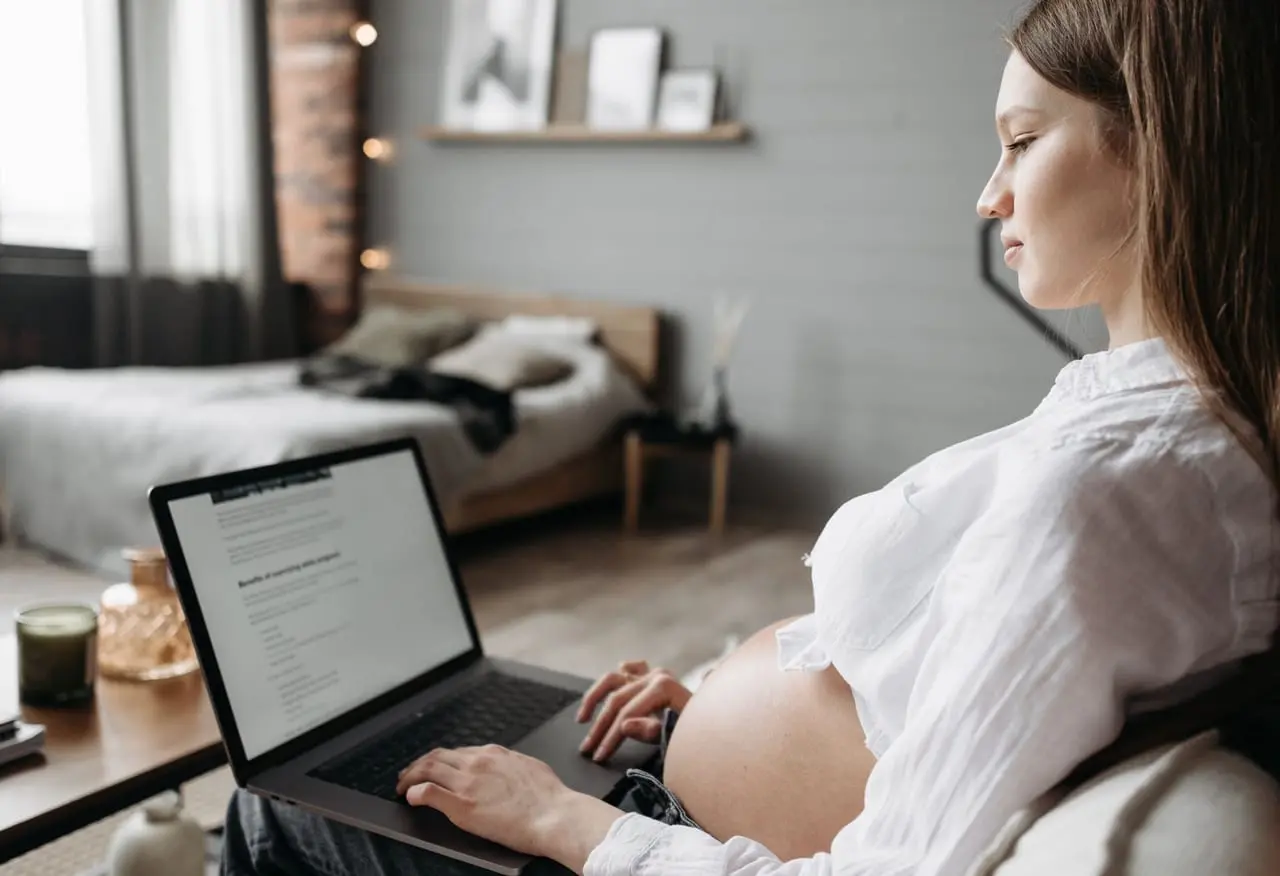 Kobieta w ciąży pracuje na laptopie w domu