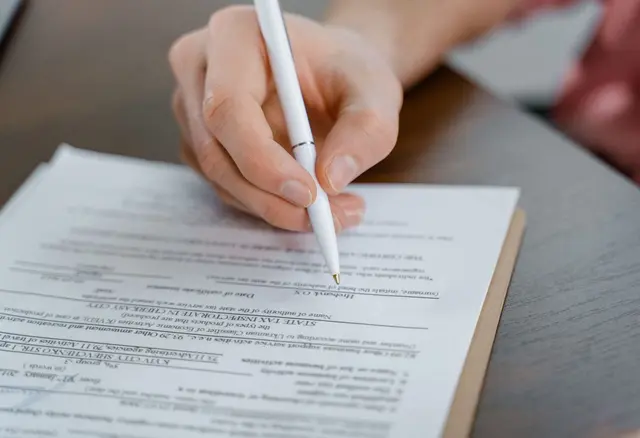 Dłoń z długopisem wypełnia formularz