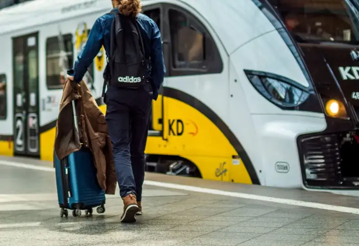 Podróżny z walizką idzie po peronie obok pociągu