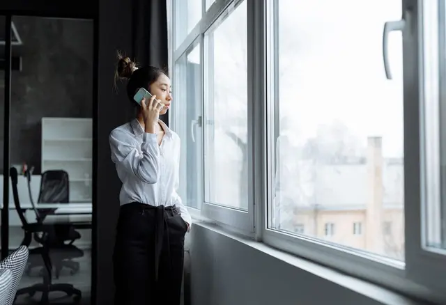 Kobieta rozmawia przez telefon przy oknie