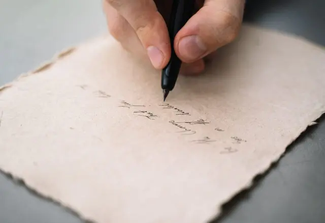 Dłoń pisze na kartce papieru