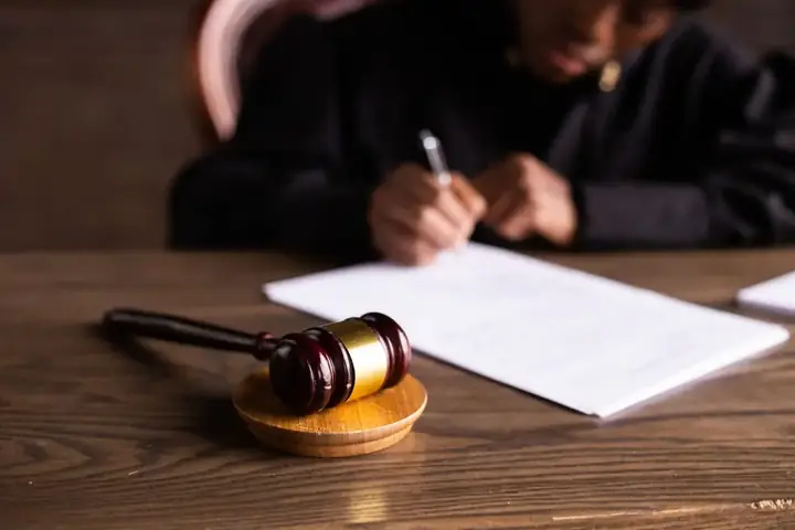 Суддівський молоток і рука, що підписує документ